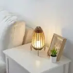 Lampe de table en bois et papier japonais, éclairant doucement un coin de chambre avec une ambiance chaleureuse et naturelle.