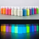 Pots de peinture phosphorescente de différentes couleurs, visibles à la lumière normale et qui brillent dans l'obscurité, parfaits pour la décoration et les projets artistiques lumineux.