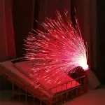 Pétard de fibre optique rouge brillant, créant un effet de feu d'artifice, posé sur une étagère avec des livres, ambiance chaleureuse et moderne.