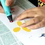 Pince à dessin pour enfants utilisant un marqueur lumineux pour créer des formes colorées sur une feuille de papier. Idéal pour stimuler la créativité et l'apprentissage ludique.