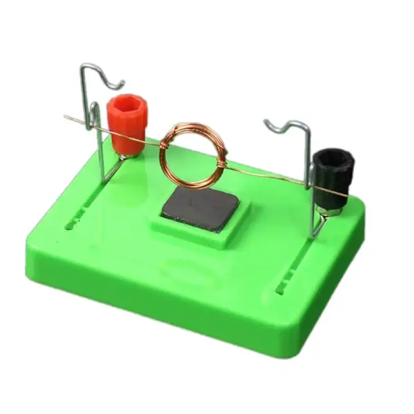 Puce de démonstration d'induction électromagnétique avec bobine de cuivre, aimants et base en plastique vert, utilisée pour illustrer le principe de l'induction électromagnétique en physique.