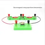 Dispositif éducatif illustrant une expérience d'oscillation électromagnétique avec bobines, aimants et fils connectés sur une base verte.