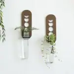 Porte-vases décoratif en métal avec design inspiré des phases lunaires, contenant des plantes vertes pour une touche naturelle et moderne.