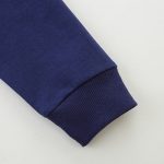 Manche de blouson en coton bleu marine avec poignets côtelés, vue rapprochée.