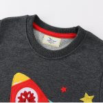 T-shirt gris foncé avec motif de fusée colorée, étoiles et éléments scientifiques, parfait pour les amateurs de science et d'astronomie.