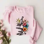 Vérifiez cette illustration de microscope entouré de fleurs colorées, parfaite pour un t-shirt original et scientifique.