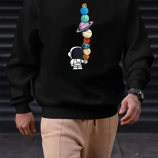 Sweatshirt noir avec motif de planètes colorées empilées et un petit astronaute, idéal pour les amateurs de science et d'astronomie. Confortable et tendance, parfait pour un look décontracté.